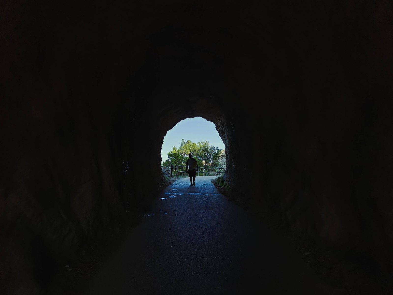 Man walking in a tunnel on Camino del Faro in Serra Gelada, Spain