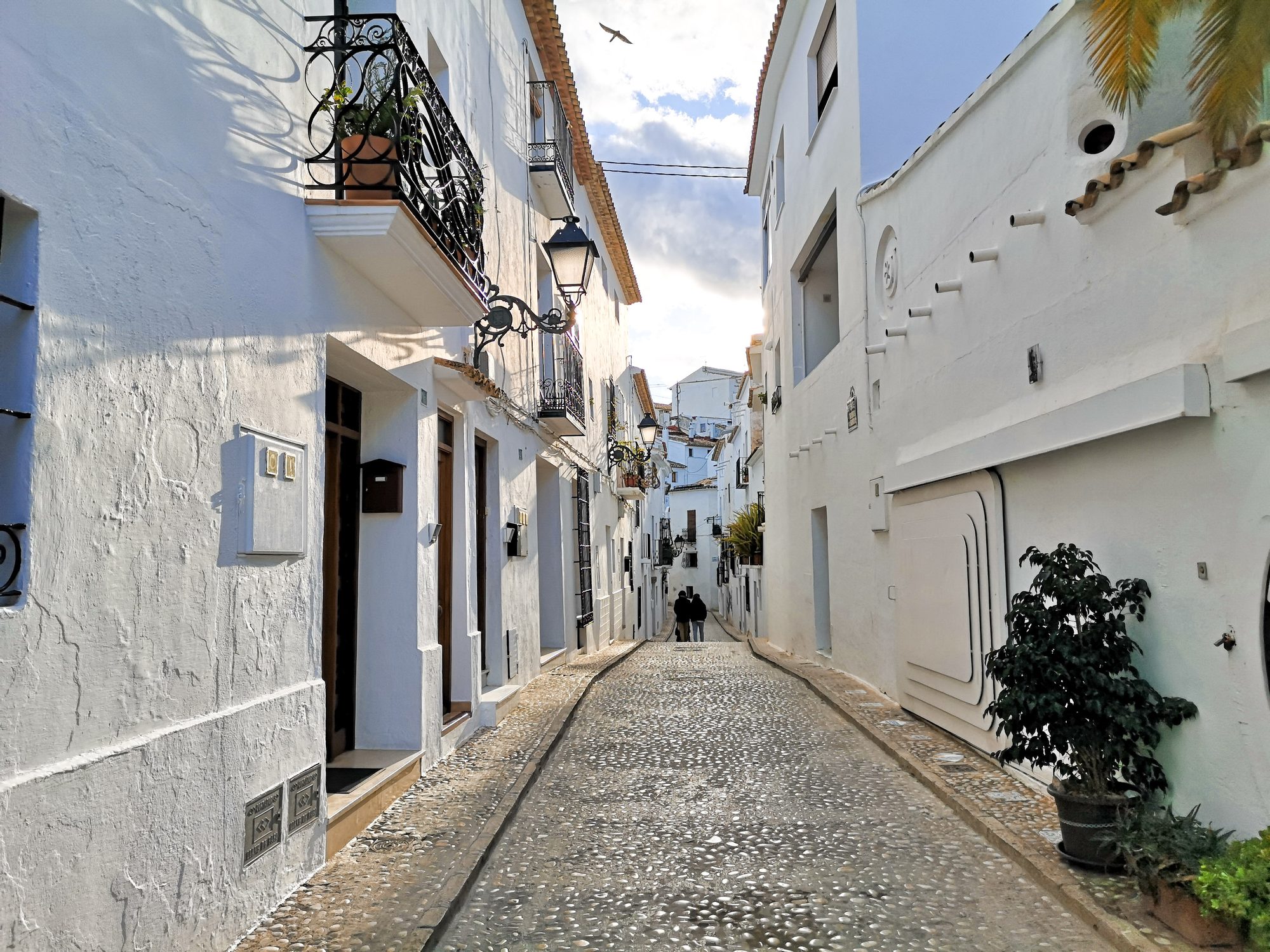 Sunlit cobbled lane with lanterns in Altea Old Town (Casco Antiguo)