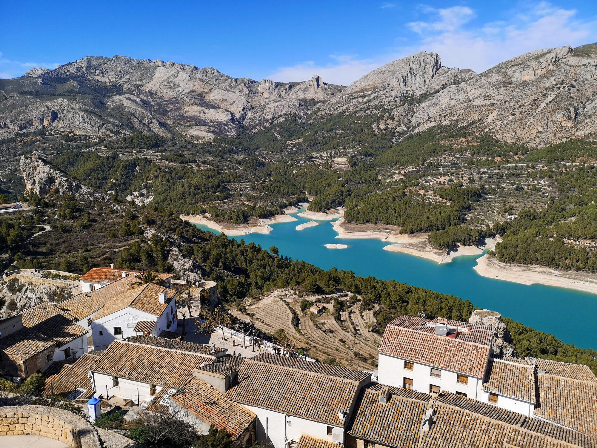 Guadalest Reservoir (Embalse de Guadalest) beyond the tiled rooftops of Guadalest